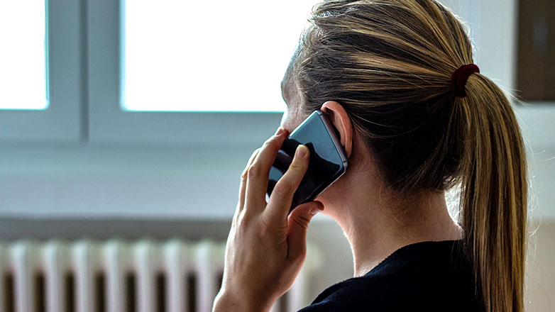 Woman looking out the window while talking on phone.