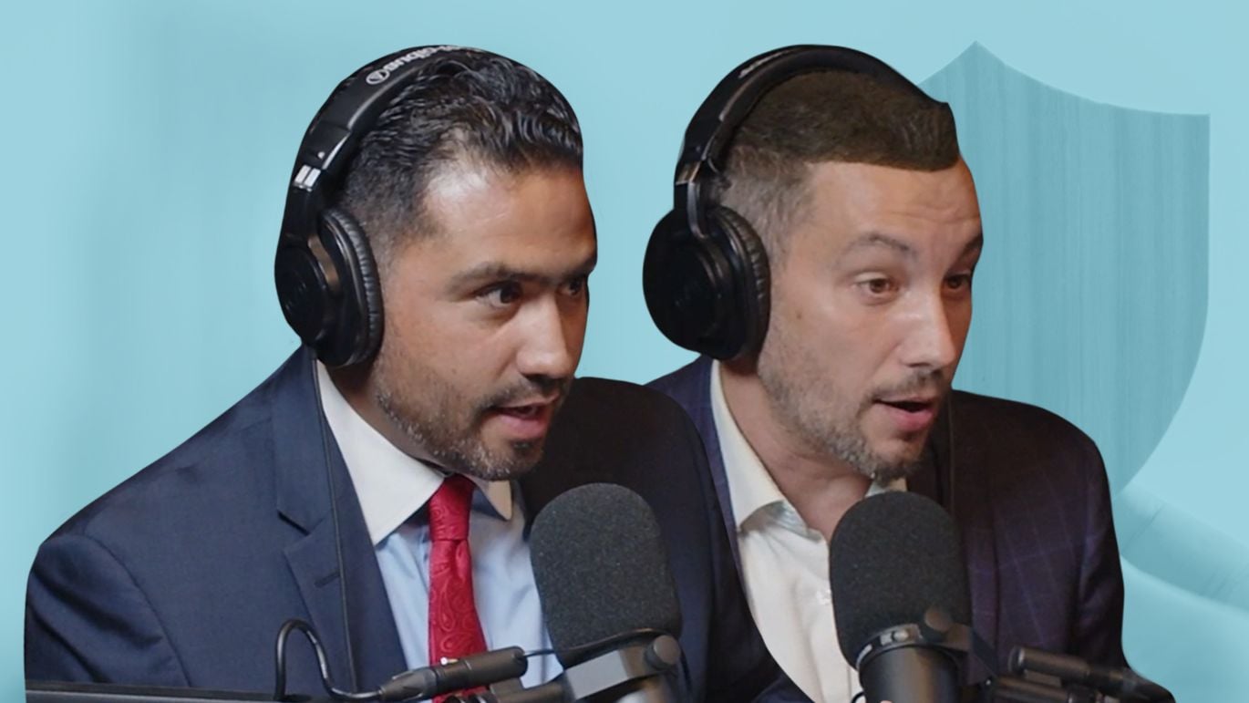 Two people wearing headphones speaking into microphones with a shield graphic in the background.