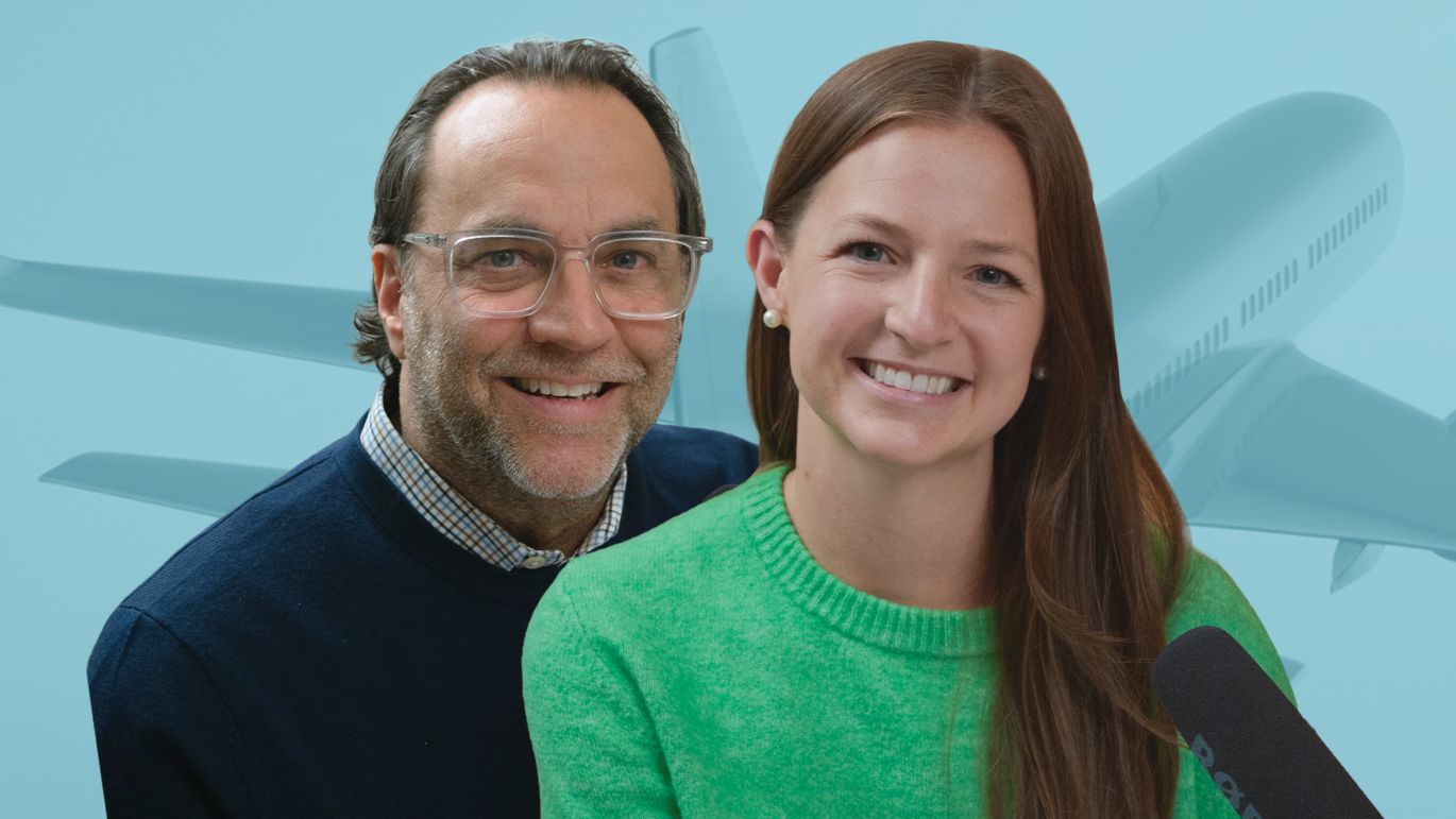 Two people posed in front of a blue-toned airplane background with a podcast microphone visible.
