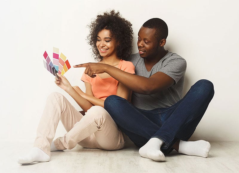 Young couple sitting together looking at paint swatches.