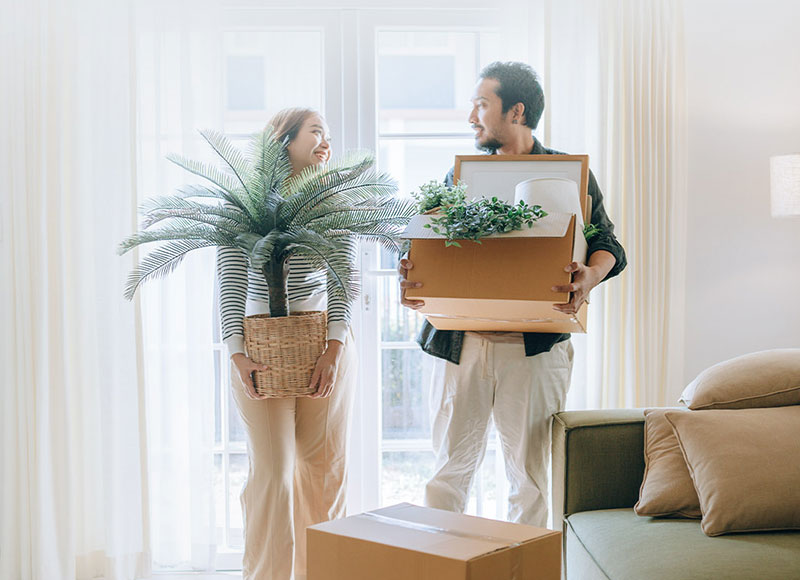 Couple moving into a new home together carrying boxes.