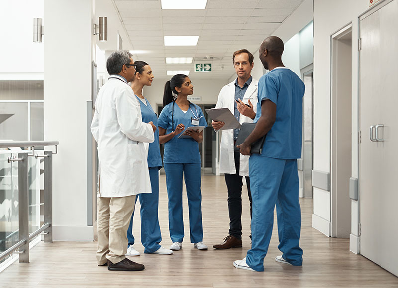 Hospital staff meets in the hallway to discuss their agenda for the day.