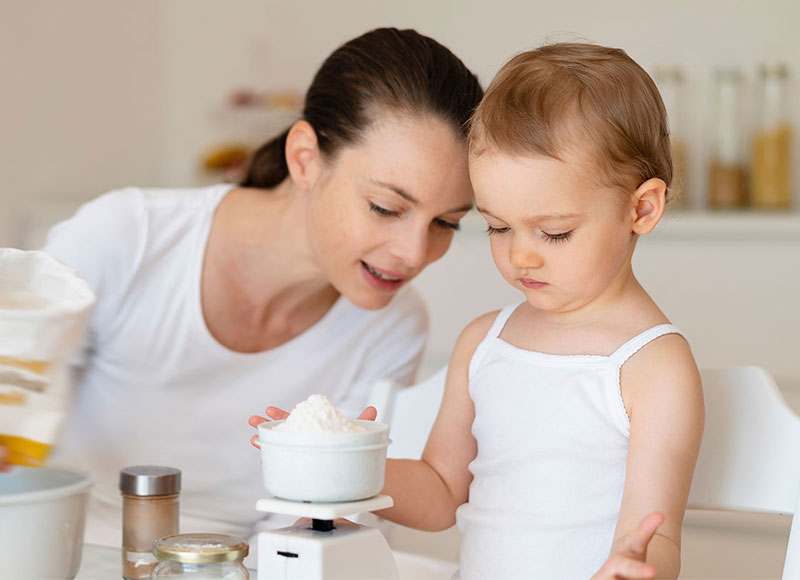 Mom and baby daughter baking together in the kitchen.