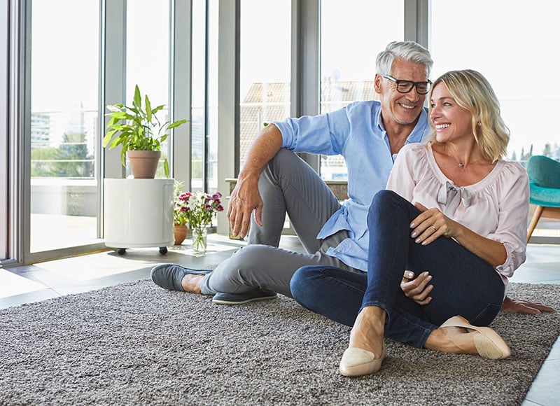 Couple sitting on their living room floor looking out the window.