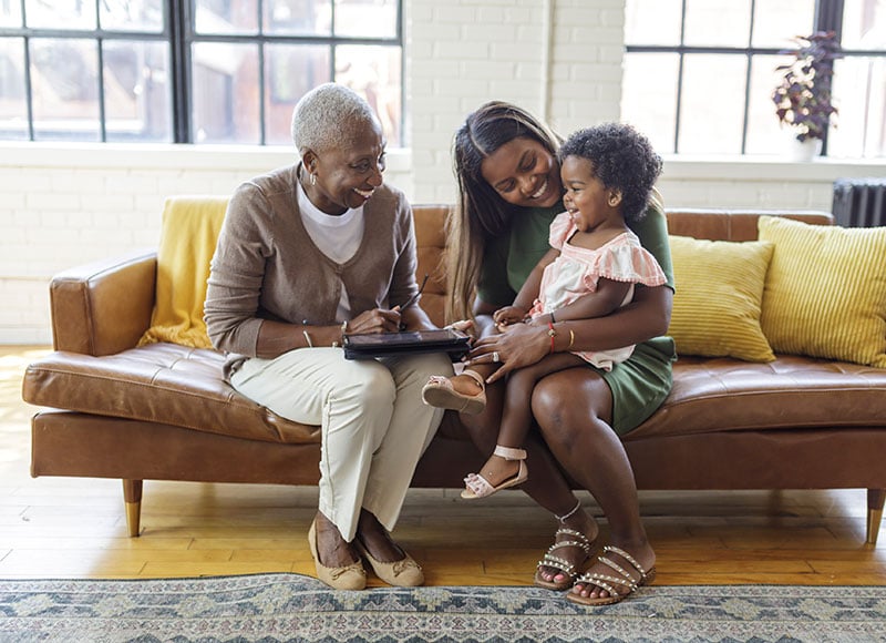 Grandma, mom and baby relax on the couch together.