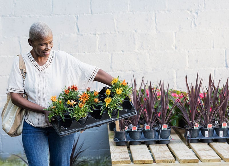 Mature woman picks up plants at a gardening store.