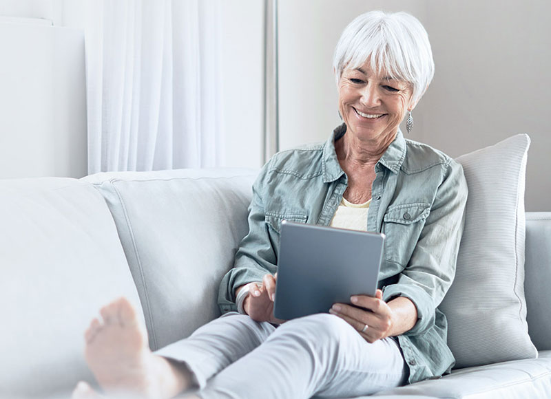 senior woman using a laptop while sitting on her couch.