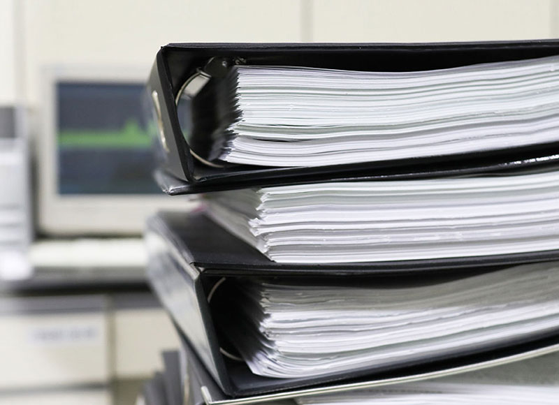 A stack of binders on a work desk.