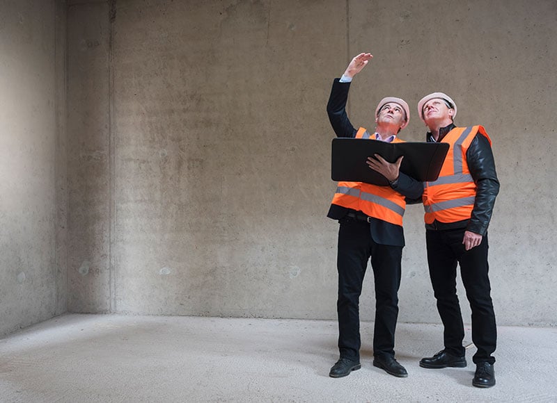 Business owner and his architect discuss building plans at a construction site