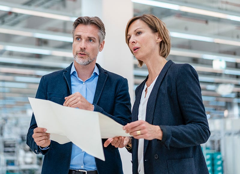 Two business owners review the layout plans for their new warehouse.