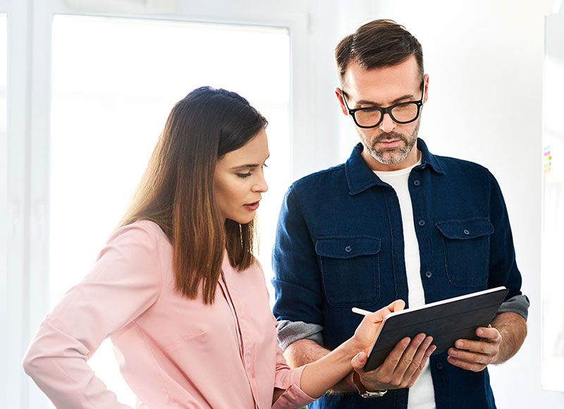 Work colleagues standing and reviewing a document on a tablet together.