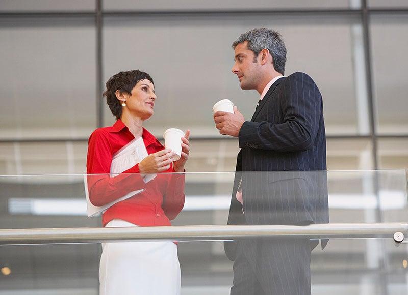 Two work colleagues have a chat over coffee.