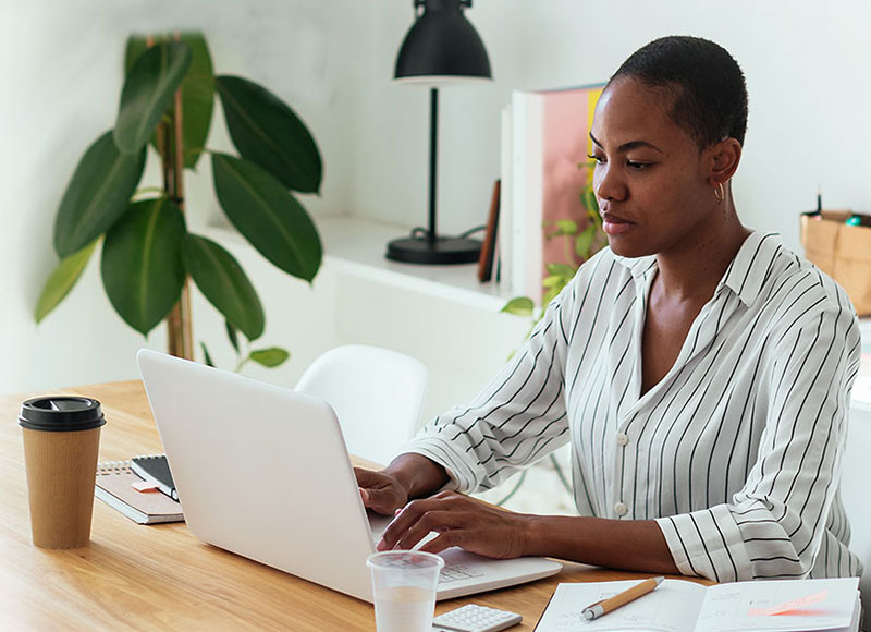 Woman works on her laptop at her desk.