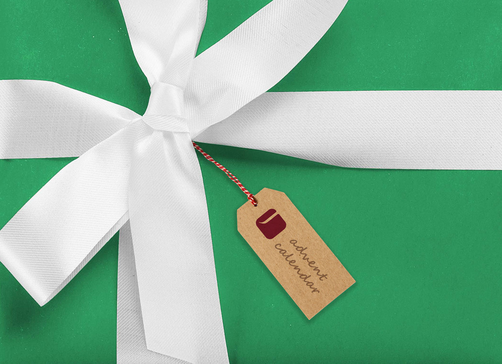 A green gift box wrapped with a white ribbon and bow, featuring a brown tag that reads 'advent calendar
