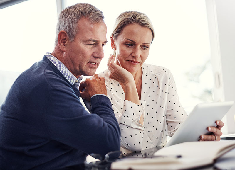 A mature couple reviews their financial paperwork together.