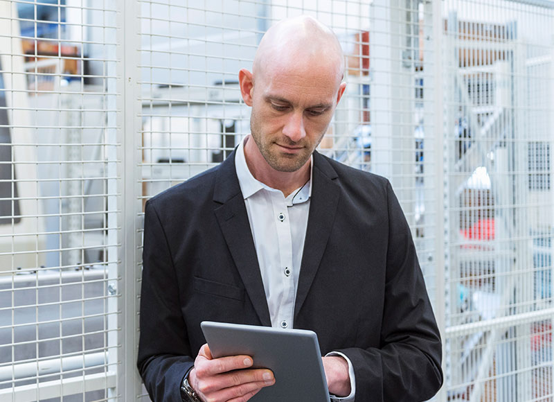 Business owner standing in his manufacturing facility and using his tablet.