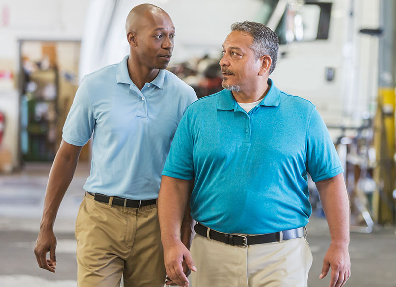 Men walking through the garage at their trucking company.