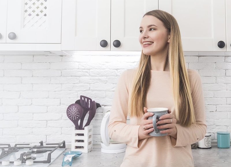 Woman enjoys her cup of coffee in her kitchen.